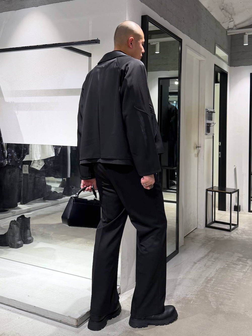 ブラック系のスラックス、ブラック系のハンドバッグ、ブラック系のドレスシューズを着用したメンズの春コーディネートの4枚目の写真