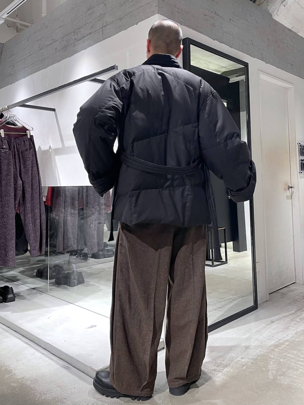 ブラウン系のスラックス、ブラック系のダウンジャケット/コート、ブラック系のドレスシューズを着用したメンズの冬コーディネートの3枚目の写真