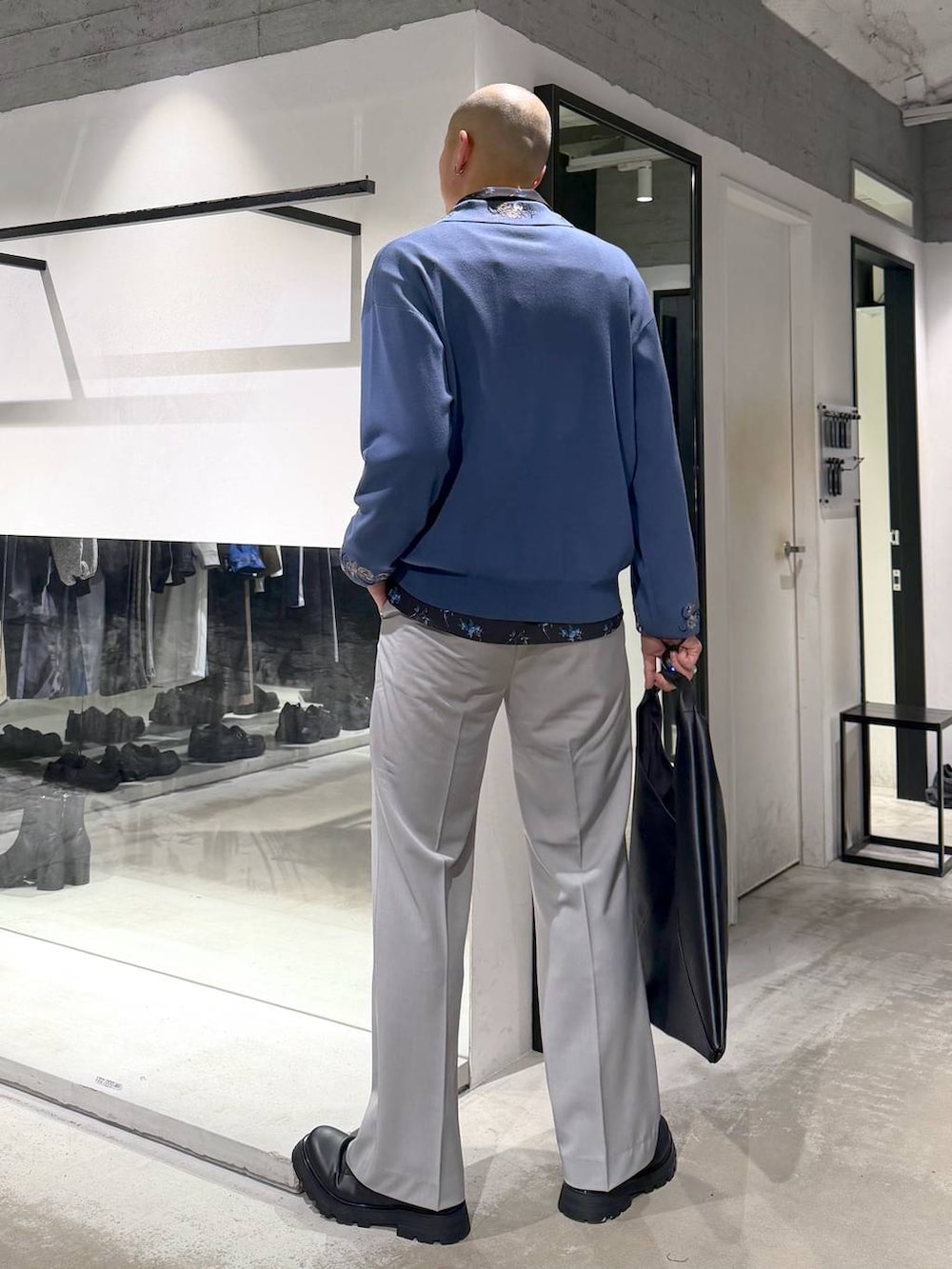 グレー系のスラックス、ブルー系のポロシャツ、ブラック系のドレスシューズを着用したメンズの春コーディネートの3枚目の写真