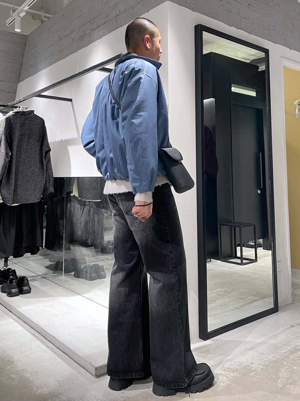 ブラック系のデニムパンツ、ブラック系のドレスシューズ、ブラック系のショルダーバッグを着用したメンズの冬コーディネートの4枚目の写真