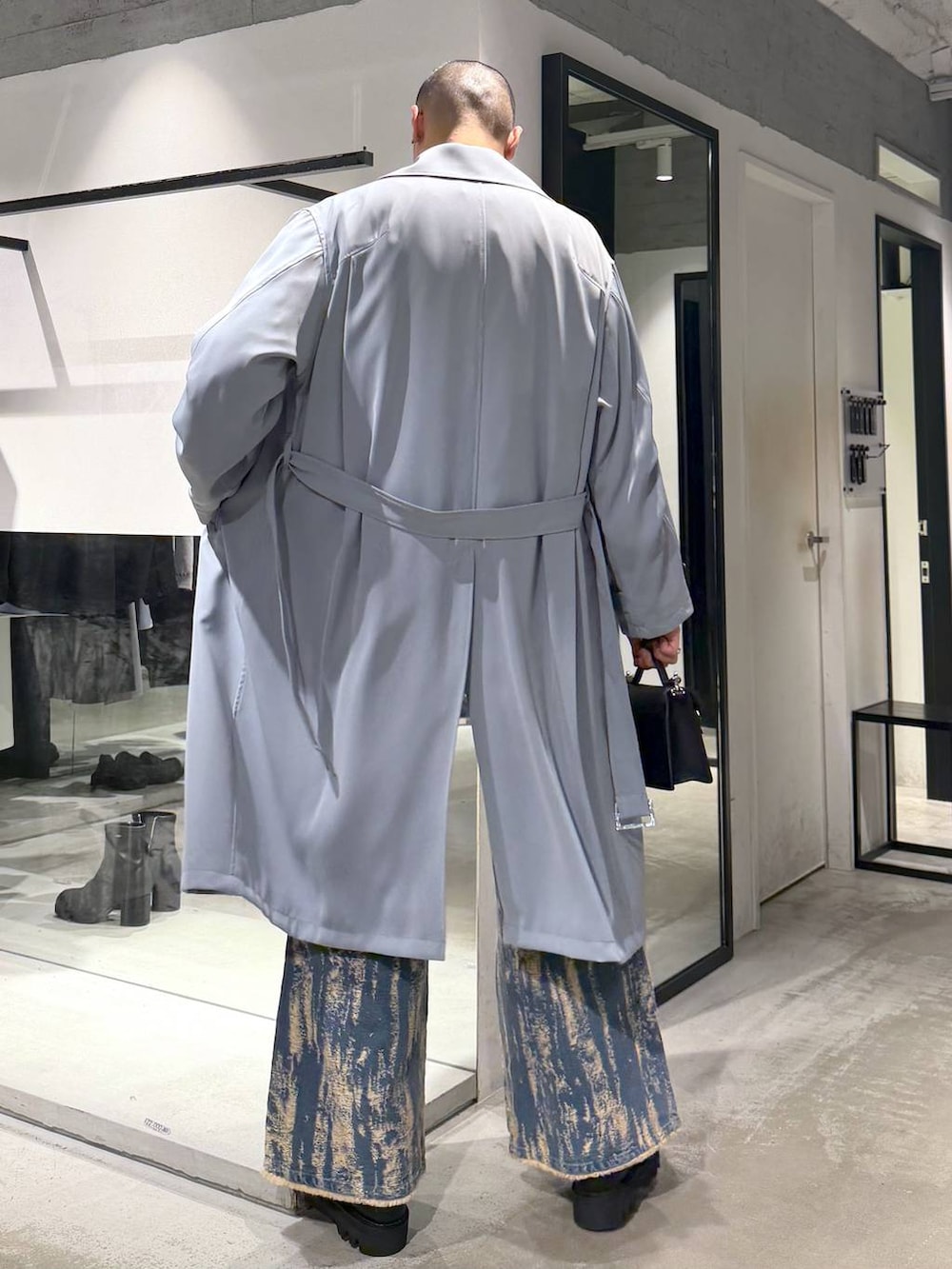 ブラック系のドレスシューズ、ブラック系のハンドバッグ、グリーン系のトレンチコートを着用したメンズの冬コーディネートの3枚目の写真