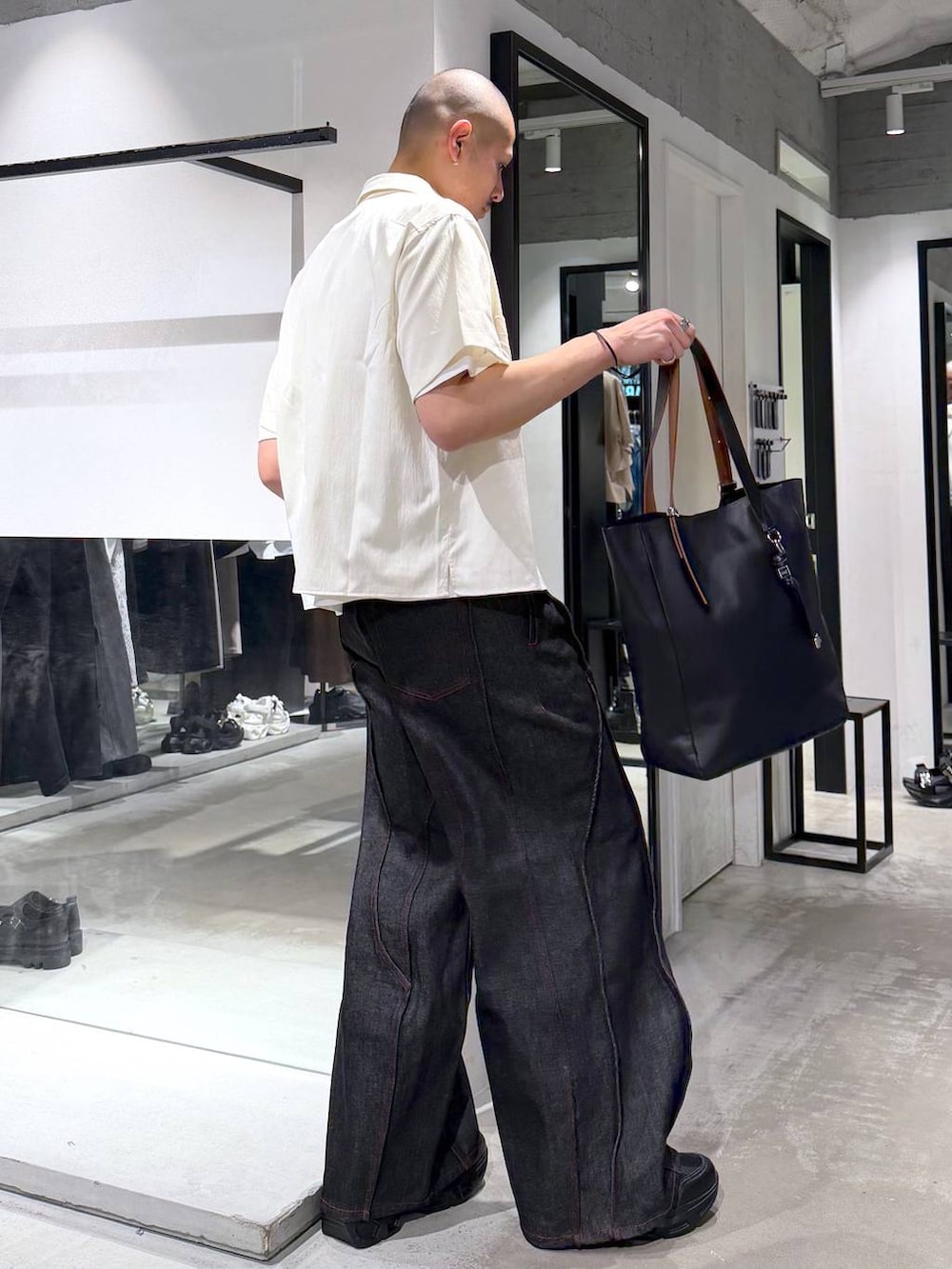 ブラック系のデニムパンツ、ブラック系のトートバッグ、ホワイト系のシャツ/ブラウスを着用したメンズの夏コーディネートの4枚目の写真