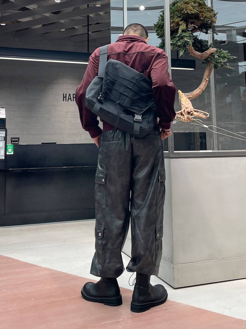 グレー系のカーゴパンツ、ブラック系のメッセンジャーバッグ、ブラック系のブーツを着用したメンズの秋コーディネートの3枚目の写真