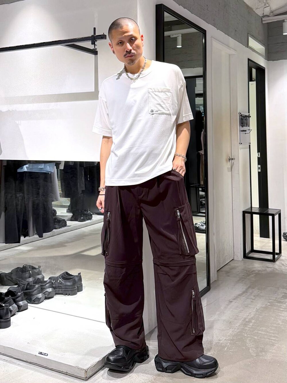 ブラック系のスニーカー、ホワイト系のTシャツ/カットソー、ブラウン系のカーゴパンツを着用したメンズの夏コーディネートの5枚目の写真