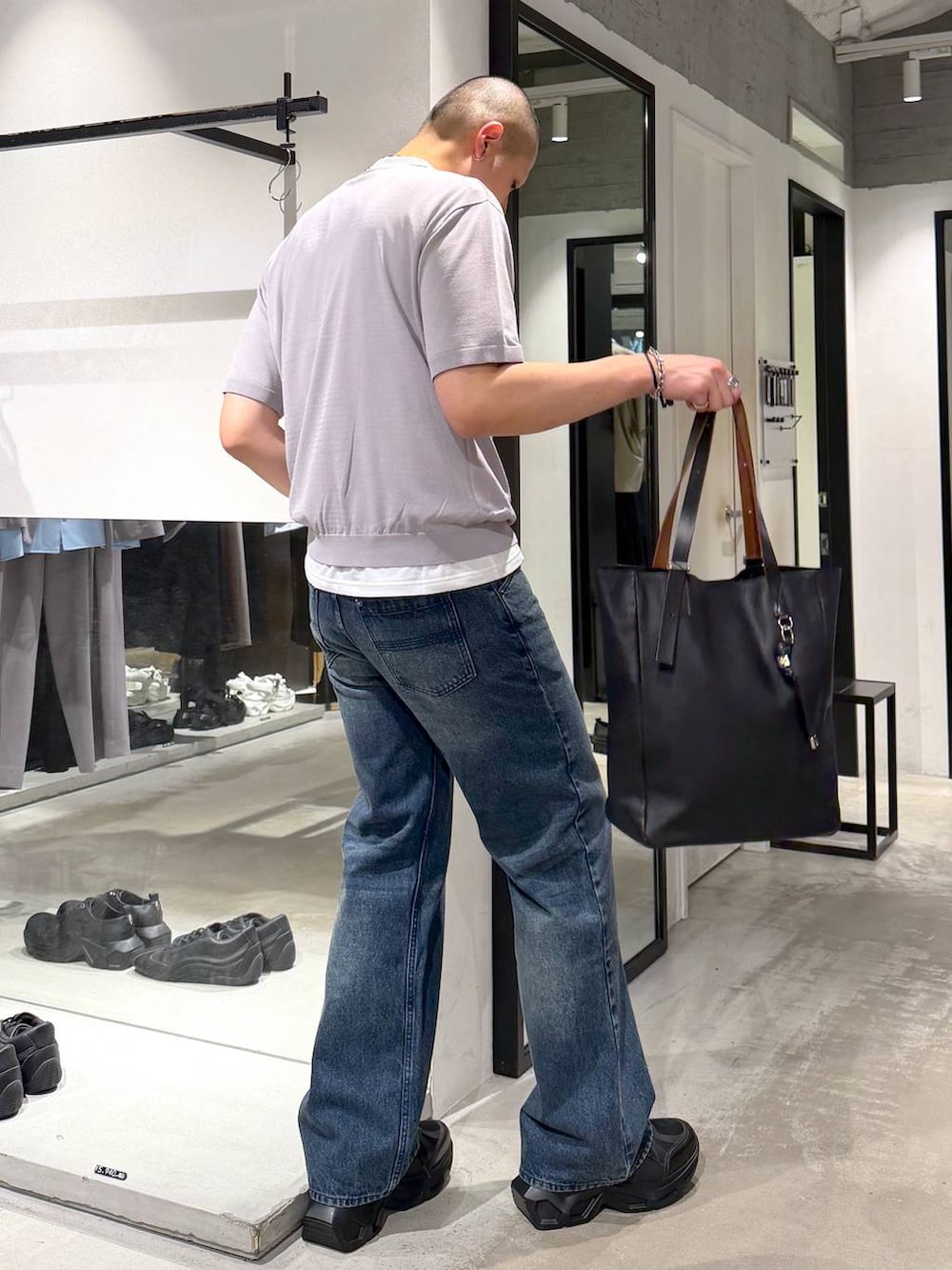 ブラック系のスニーカー、ブラック系のトートバッグ、ブルー系のデニムパンツを着用したメンズの夏コーディネートの4枚目の写真