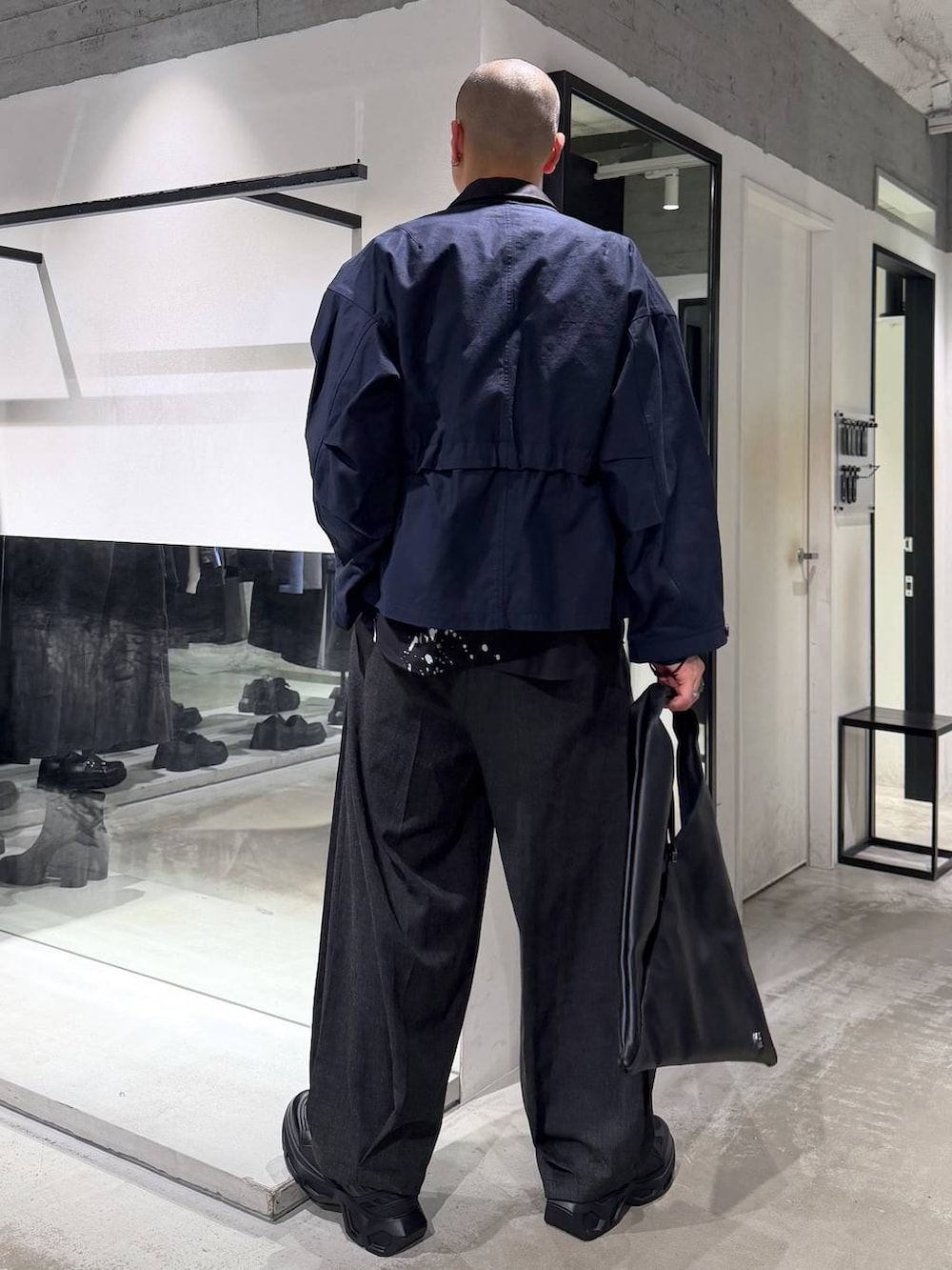 ブラック系のスニーカー、ブラック系のスラックス、ブラック系のトートバッグを着用したメンズの春コーディネートの3枚目の写真