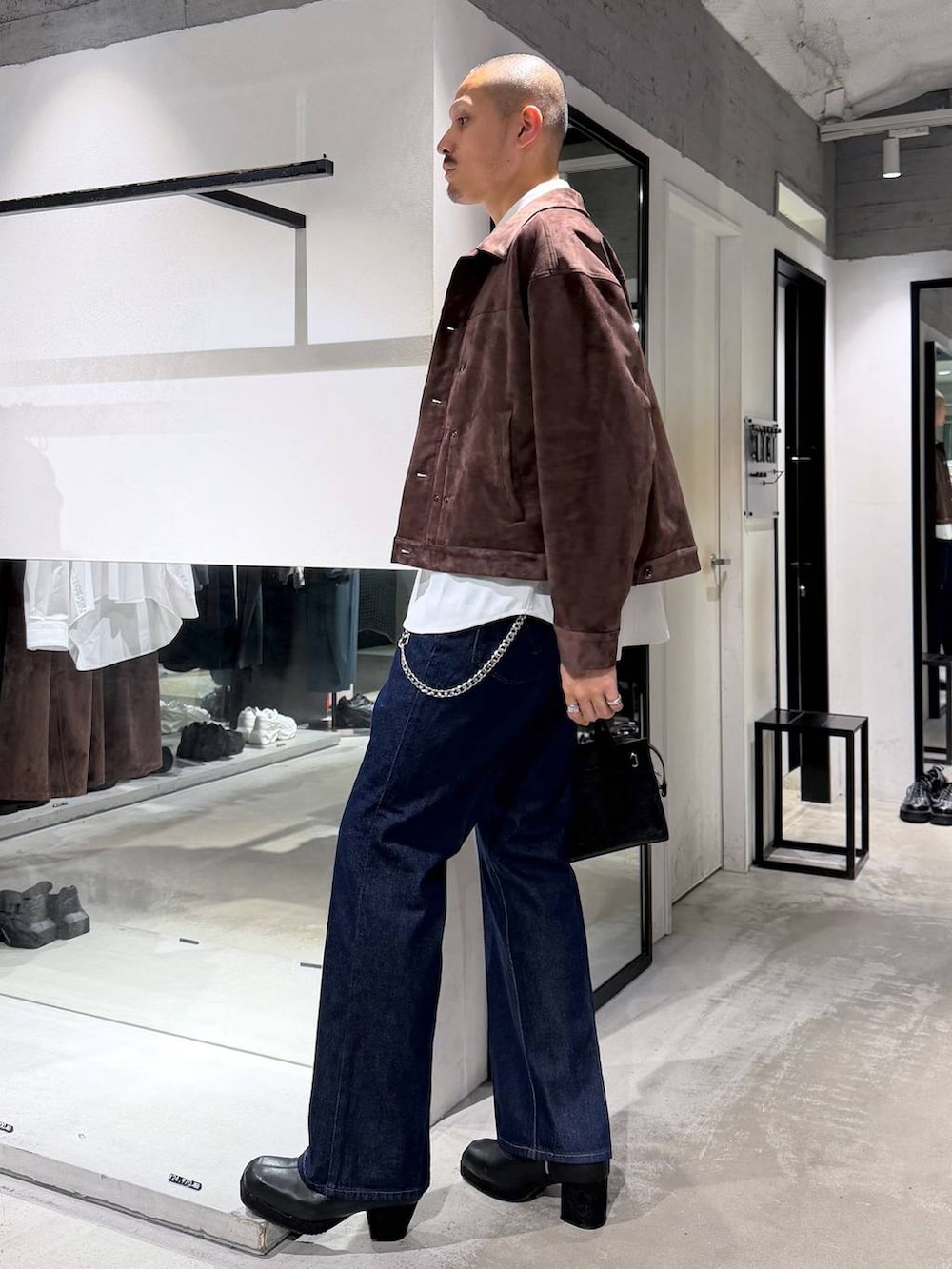 ブラック系のボストンバッグ、ブラック系のブーツ、ブルー系のデニムパンツを着用したメンズの秋コーディネートの2枚目の写真