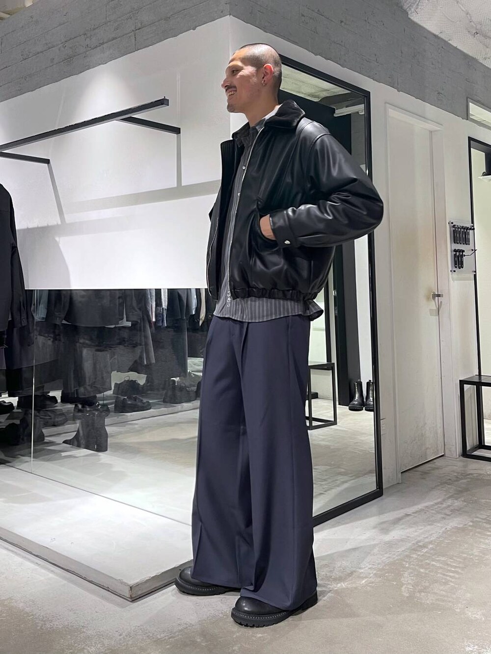 ブラック系のブルゾン、ブルー系のスラックス、ブラック系のショルダーバッグを着用したメンズの冬コーディネートの2枚目の写真