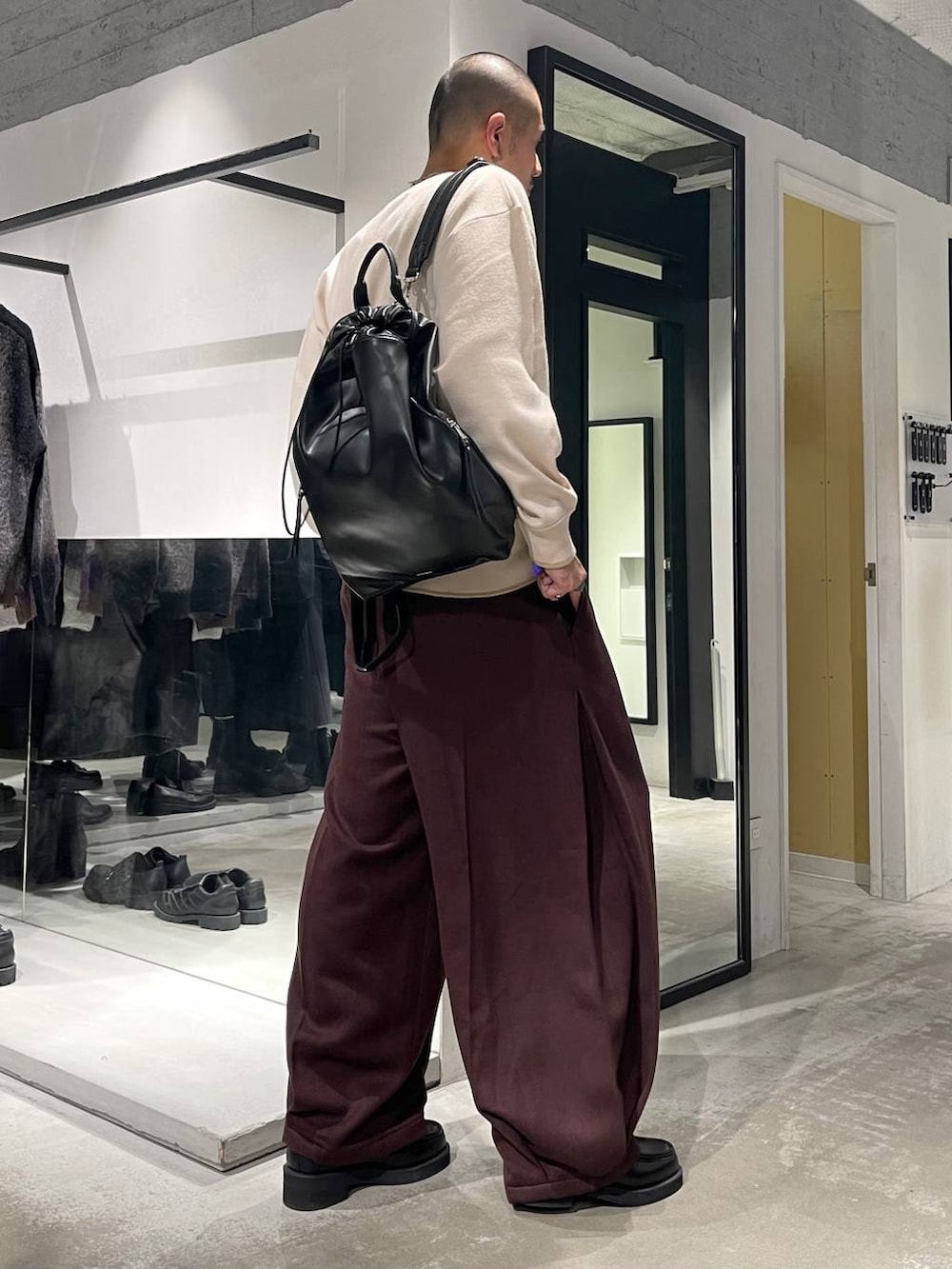 ブラック系のローファー、ブラック系のバックパック/リュック、ホワイト系のニット/セーターを着用したメンズの秋コーディネートの4枚目の写真