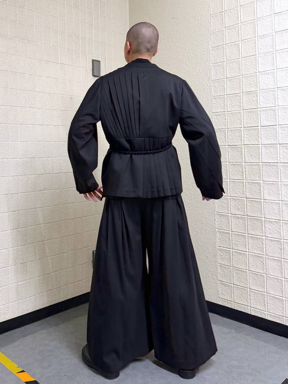 ブラック系のノーカラージャケットを着用したメンズの春コーディネートの4枚目の写真