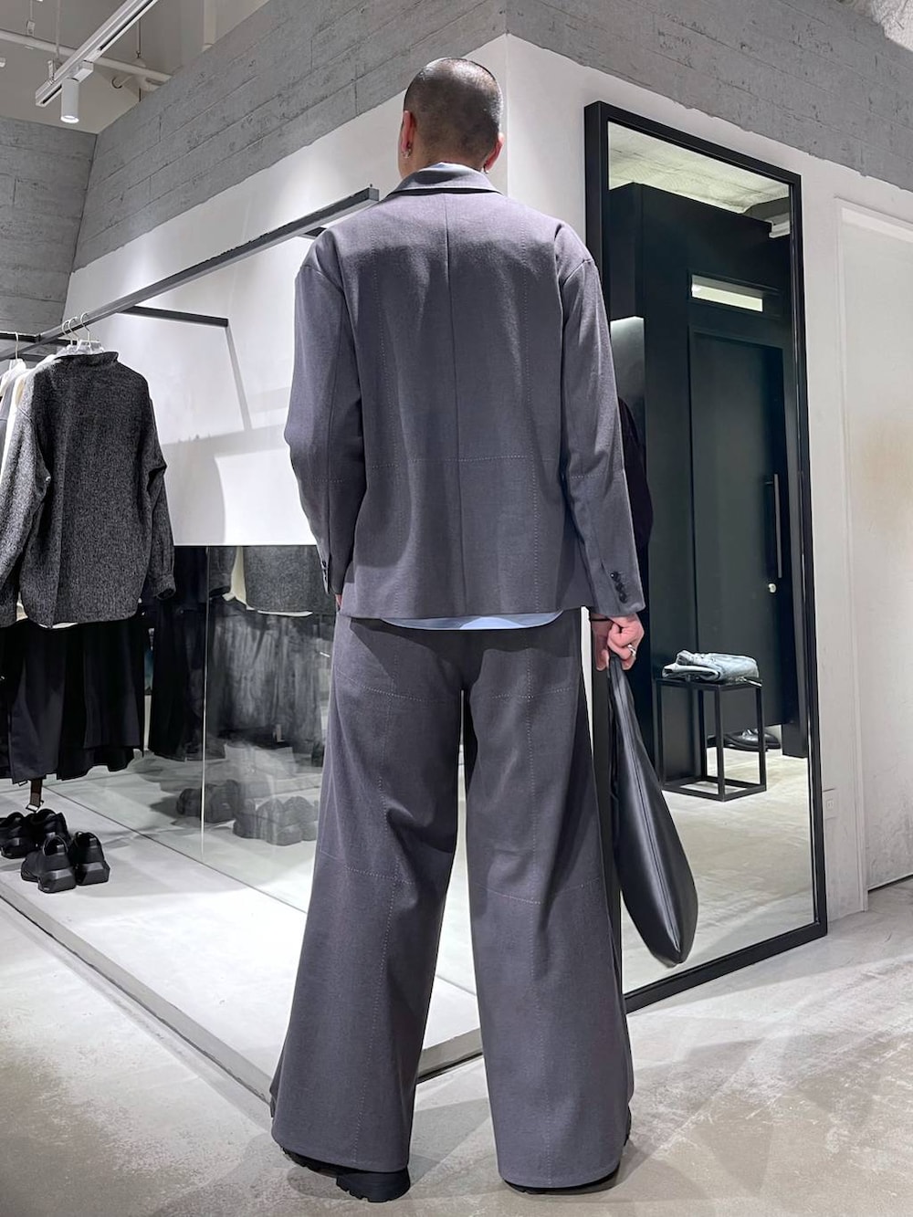 ブラック系のトートバッグ、ブラック系のドレスシューズ、グレー系のテーラードジャケットを着用したメンズの冬コーディネートの3枚目の写真