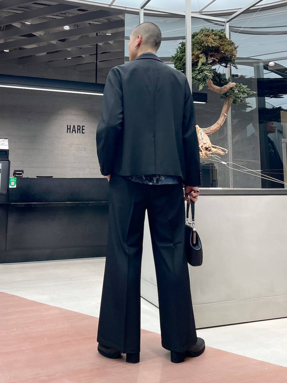 ブラック系のショルダーバッグ、ブラック系のブーツ、ブラック系のスラックスを着用したメンズの秋コーディネートの3枚目の写真