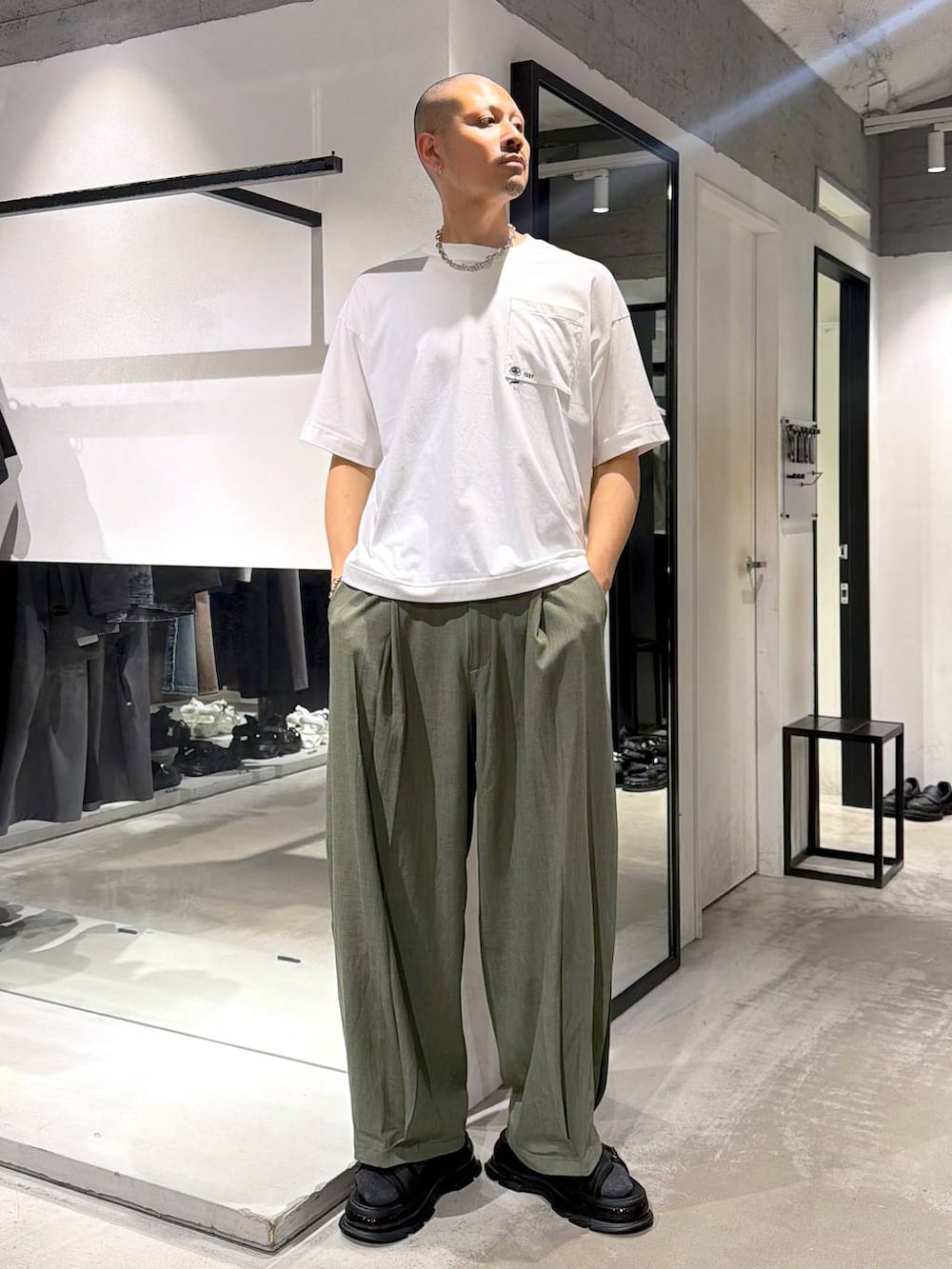 ブラック系のトートバッグ、ホワイト系のTシャツ/カットソー、グリーン系のスラックスを着用したメンズの夏コーディネートの5枚目の写真
