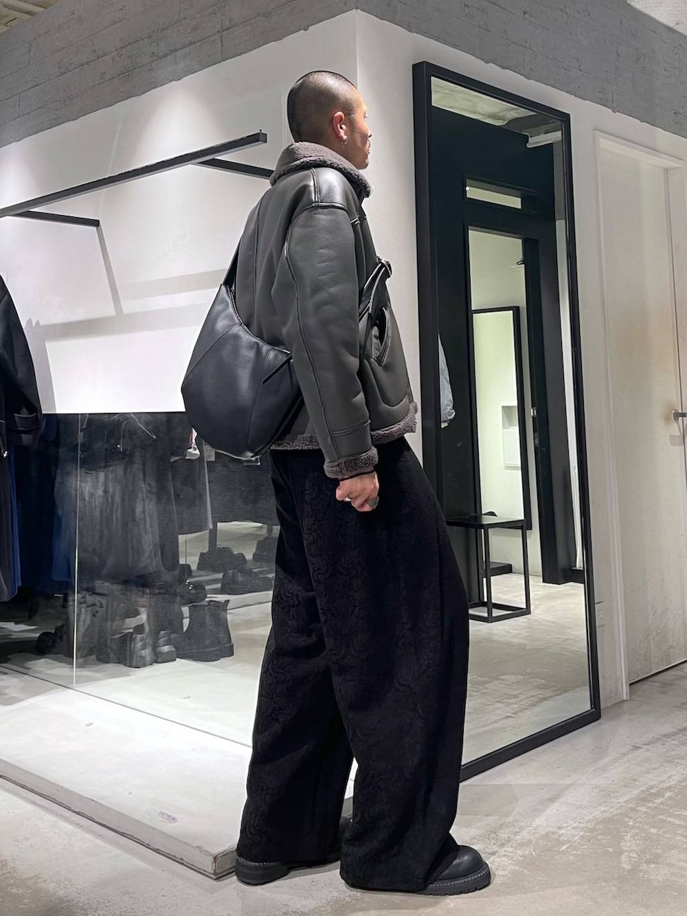 グレー系のブルゾン、ブラック系のブーツ、ブラック系のショルダーバッグを着用したメンズの冬コーディネートの4枚目の写真
