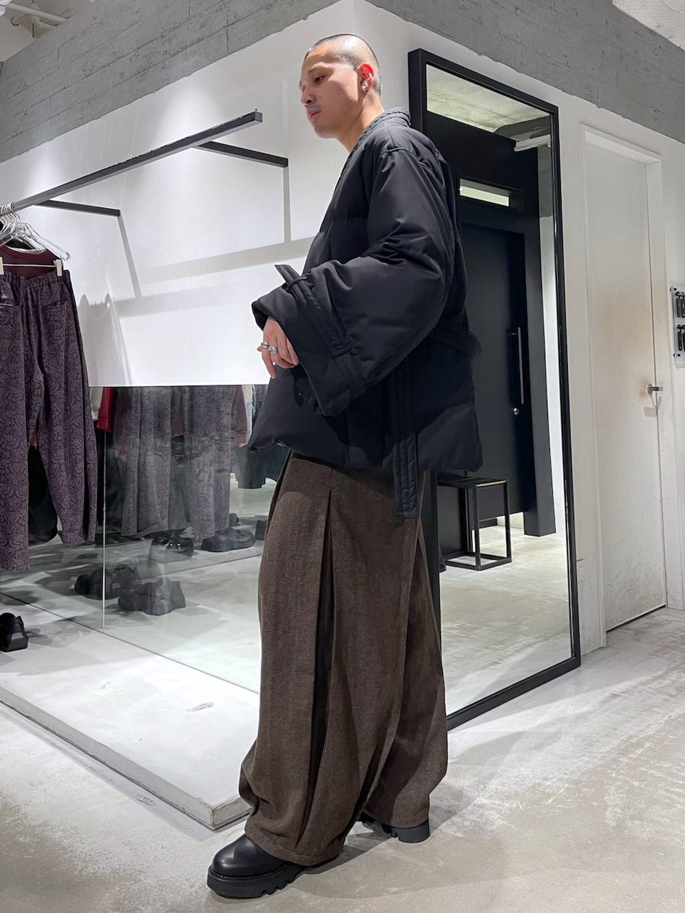 ブラウン系のスラックス、ブラック系のダウンジャケット/コート、ブラック系のドレスシューズを着用したメンズの冬コーディネートの2枚目の写真