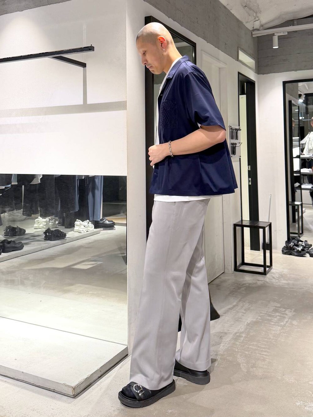 グレー系のスラックス、ブラック系のサンダル、ブラック系のトートバッグを着用したメンズの春コーディネートの2枚目の写真