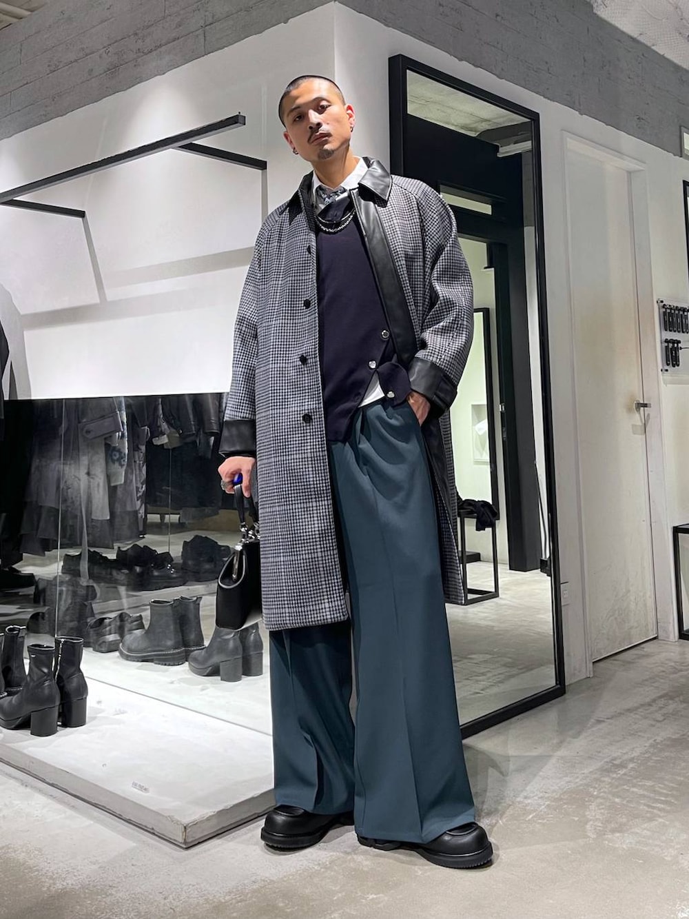 ホワイト系のネクタイ、ベージュ系のステンカラーコート、ブラック系のショルダーバッグを着用したメンズの秋コーディネートの2枚目の写真