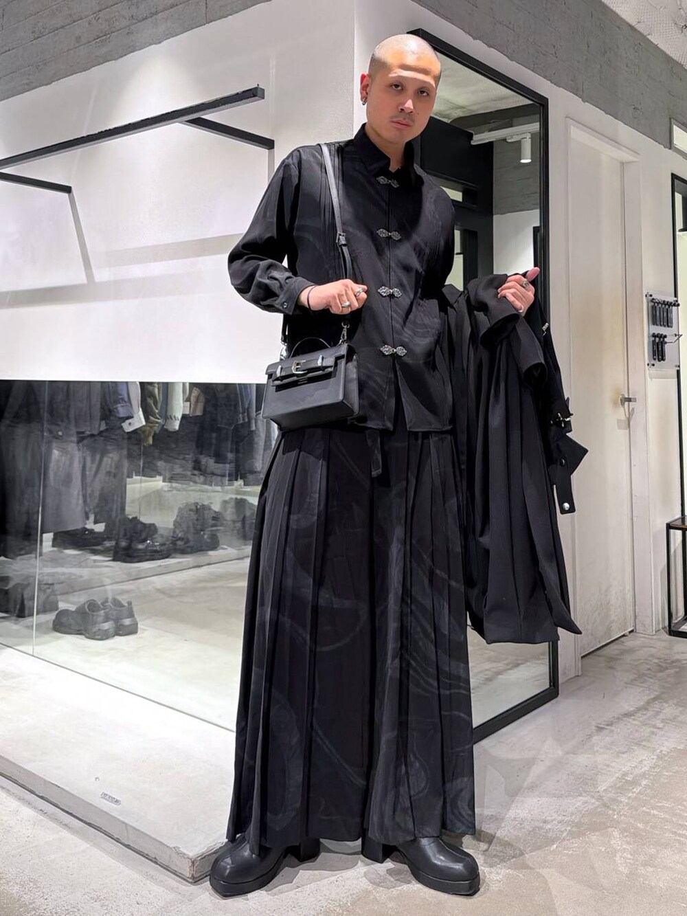 グレー系のその他パンツ、ブラック系のブーツ、ブラック系のハンドバッグを着用したメンズの冬コーディネートの5枚目の写真