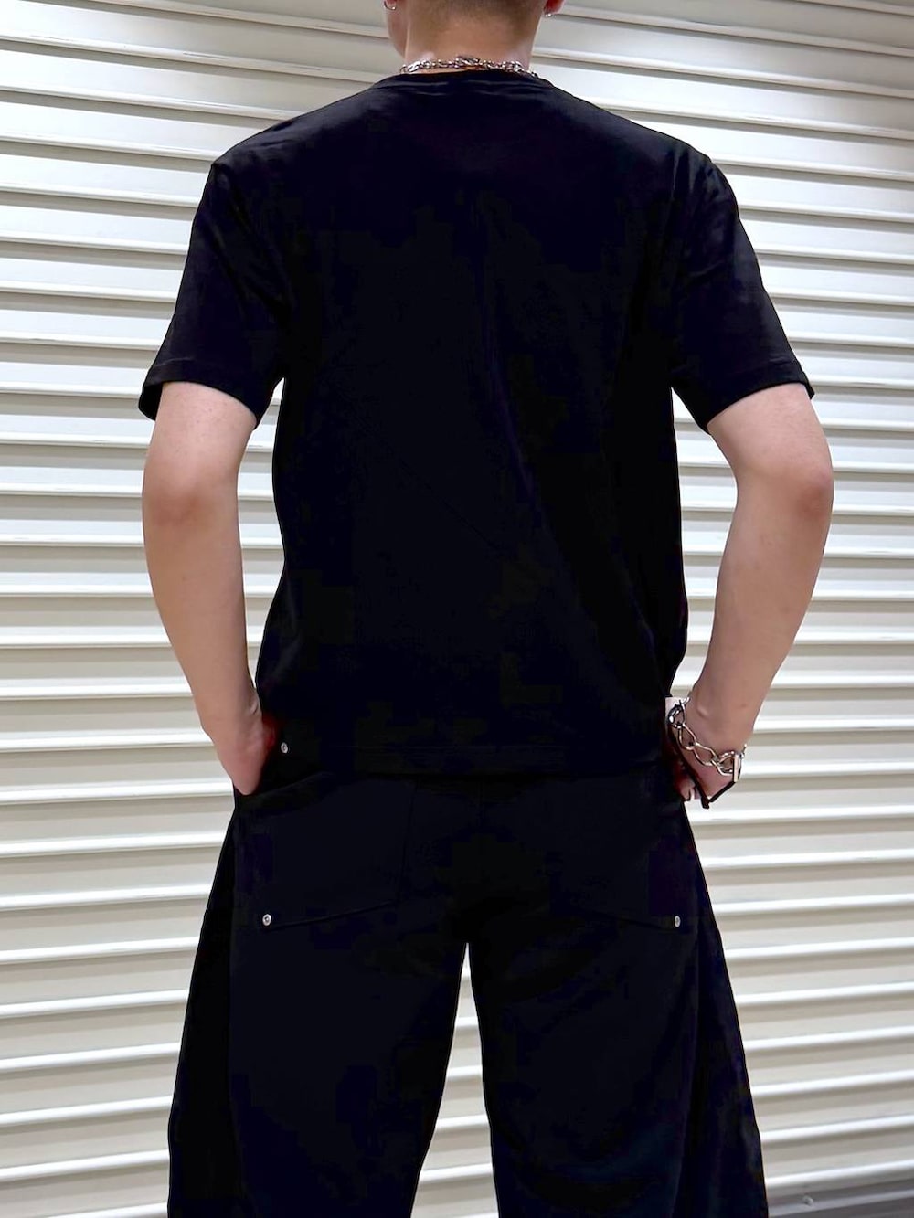 ブラック系のスラックス、ブラック系のTシャツ/カットソー、ブラック系のスニーカーを着用したメンズの夏コーディネートの6枚目の写真
