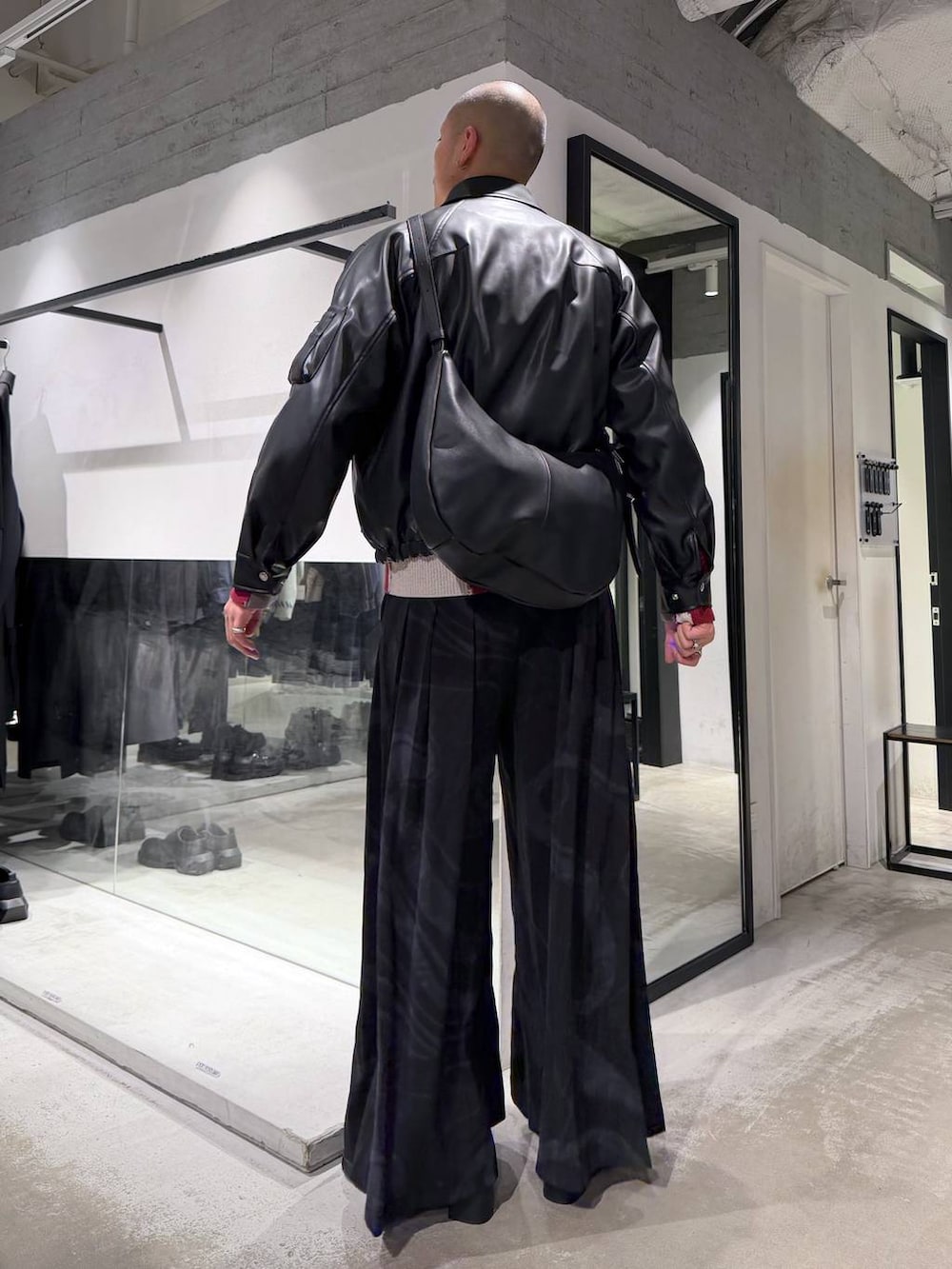 ブラック系のブルゾン、グレー系のその他パンツ、レッド系のカーディガン/ボレロを着用したメンズの冬コーディネートの3枚目の写真