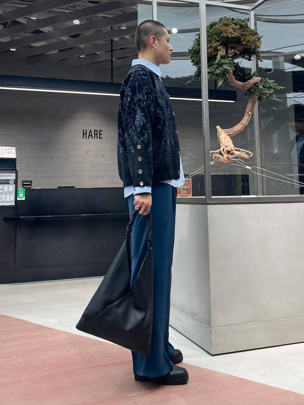 ブルー系のスラックス、ブラック系のカーディガン/ボレロ、ブラック系のトートバッグを着用したメンズの秋コーディネートの4枚目の写真