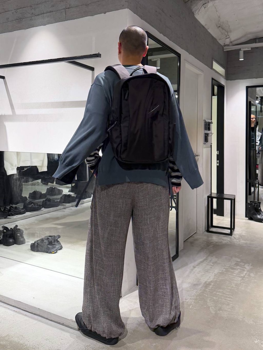 ブラック系のバックパック/リュック、グレー系のスラックス、グリーン系のカーディガン/ボレロを着用したメンズの春コーディネートの4枚目の写真