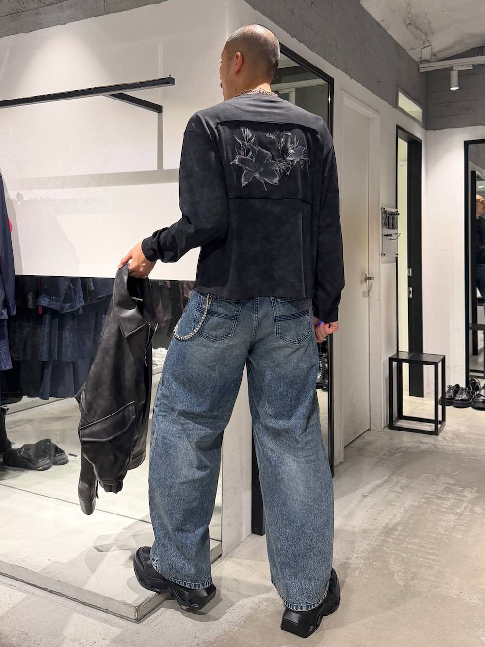 ブルー系のデニムパンツ、ブラック系のTシャツ/カットソー、ブラック系のスニーカーを着用したメンズの秋コーディネートの6枚目の写真