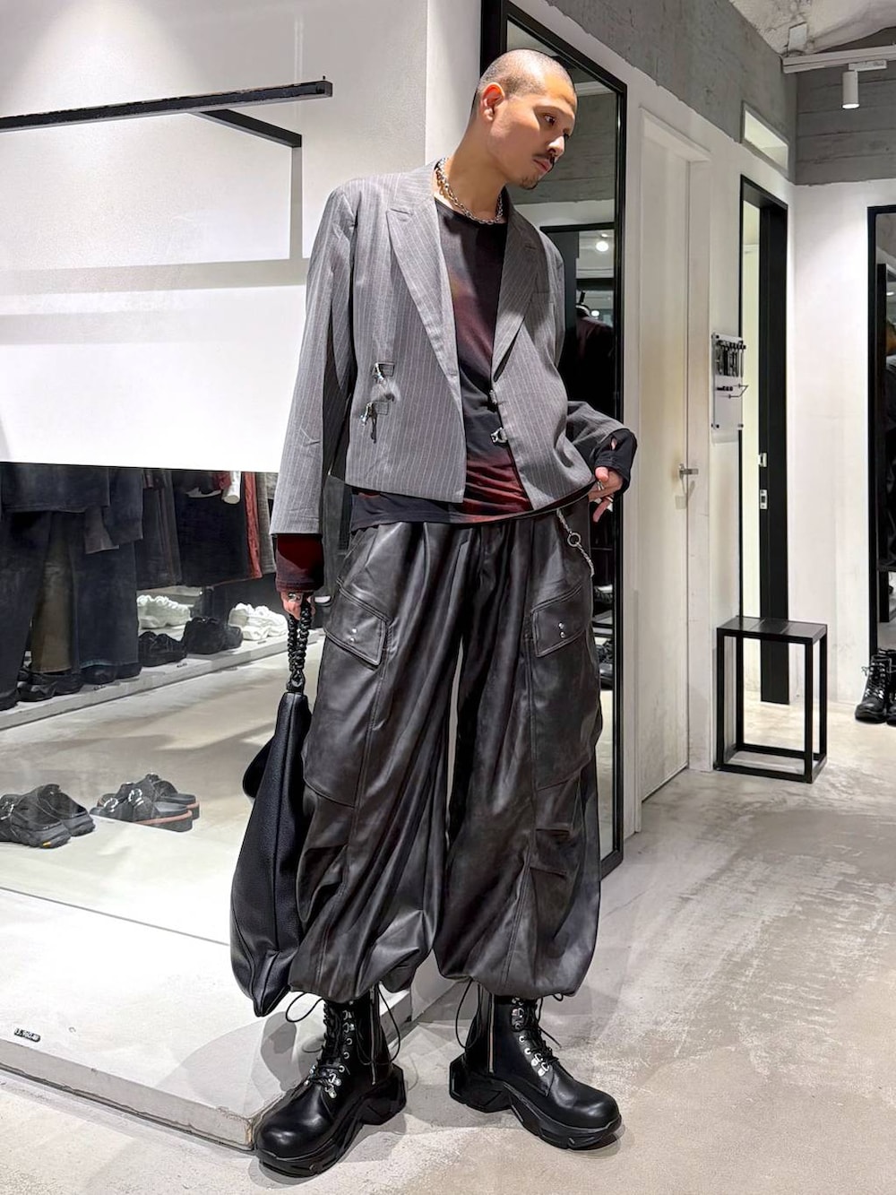 ブラック系のトートバッグ、ブラック系のブーツ、オレンジ系のTシャツ/カットソーを着用したメンズの秋コーディネートの5枚目の写真