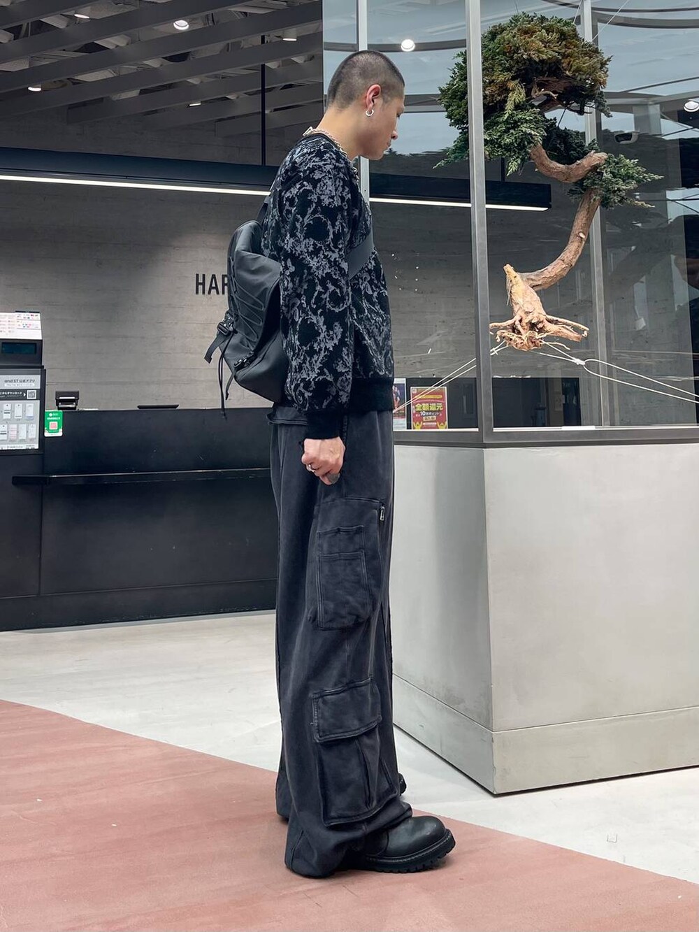 グレー系のニット/セーター、ブラック系のメッセンジャーバッグ、ブラック系のスウェットパンツを着用したメンズの秋コーディネートの4枚目の写真