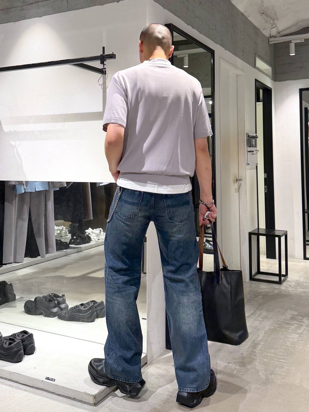 ブラック系のスニーカー、ブラック系のトートバッグ、ブルー系のデニムパンツを着用したメンズの夏コーディネートの3枚目の写真