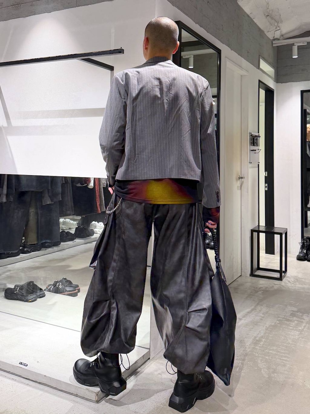 ブラック系のトートバッグ、ブラック系のブーツ、オレンジ系のTシャツ/カットソーを着用したメンズの秋コーディネートの3枚目の写真