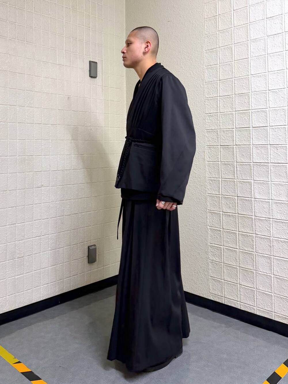 ブラック系のノーカラージャケットを着用したメンズの春コーディネートの3枚目の写真