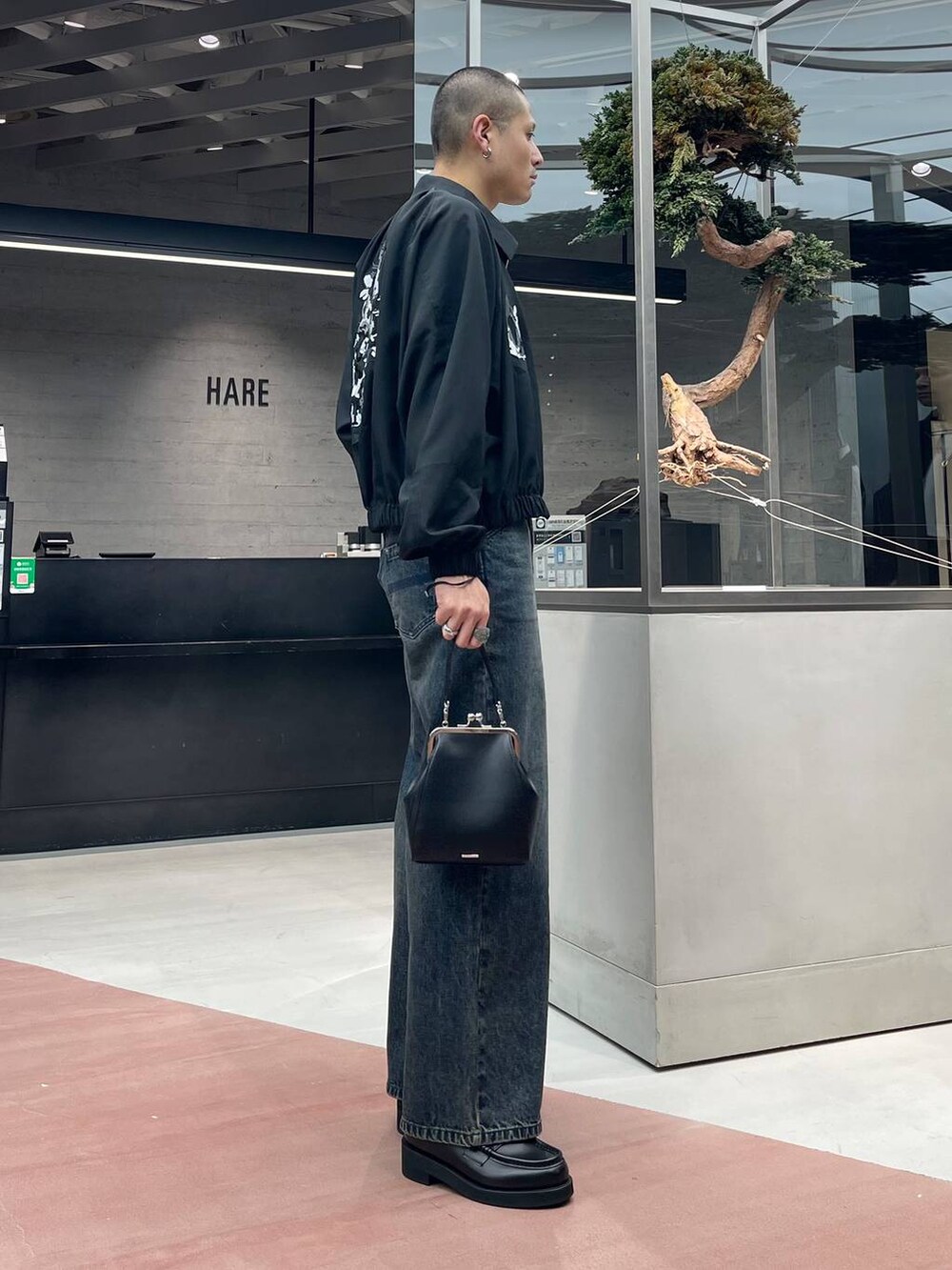 ブラック系のローファー、ブルー系のデニムパンツ、ブラック系のショルダーバッグを着用したメンズの秋コーディネートの2枚目の写真