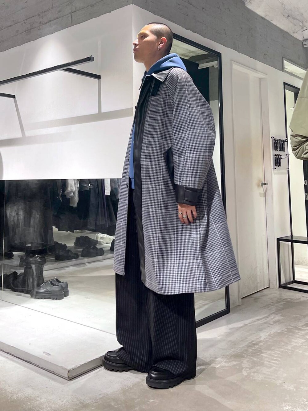 ベージュ系のステンカラーコート、ブラック系のトートバッグ、ブラック系のドレスシューズを着用したメンズの秋コーディネートの2枚目の写真