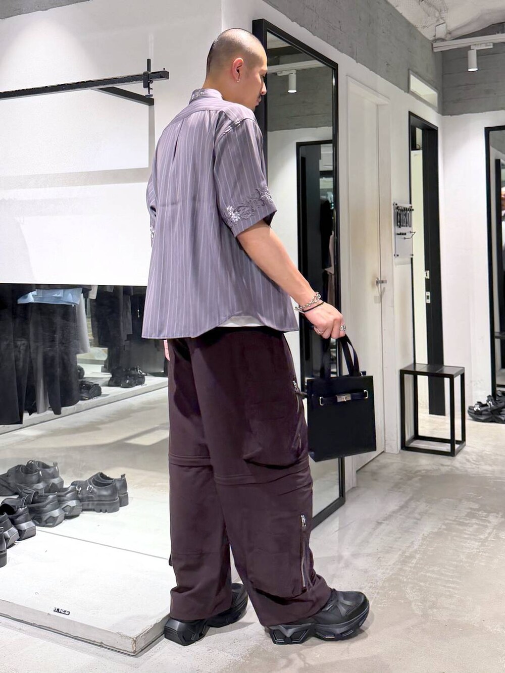 ブラック系のスニーカー、ホワイト系のTシャツ/カットソー、ブラウン系のカーゴパンツを着用したメンズの夏コーディネートの4枚目の写真