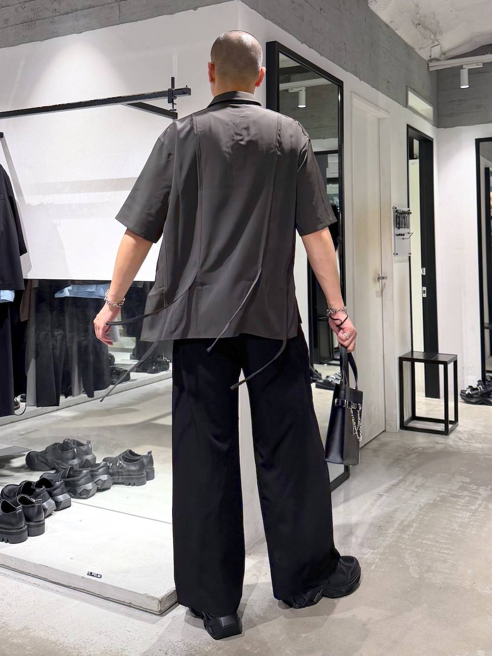 ブラック系のスニーカー、ブラック系のスラックス、ブラック系のショルダーバッグを着用したメンズの夏コーディネートの3枚目の写真