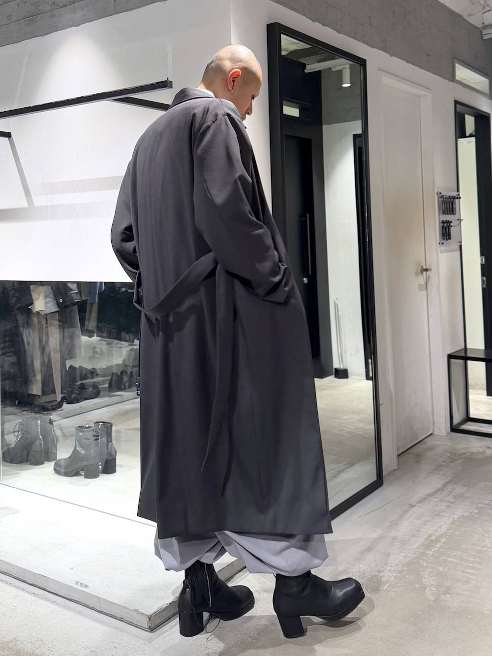 ブルー系のポロシャツ、ブラック系のブーツ、ブラック系のハンドバッグを着用したメンズの冬コーディネートの4枚目の写真