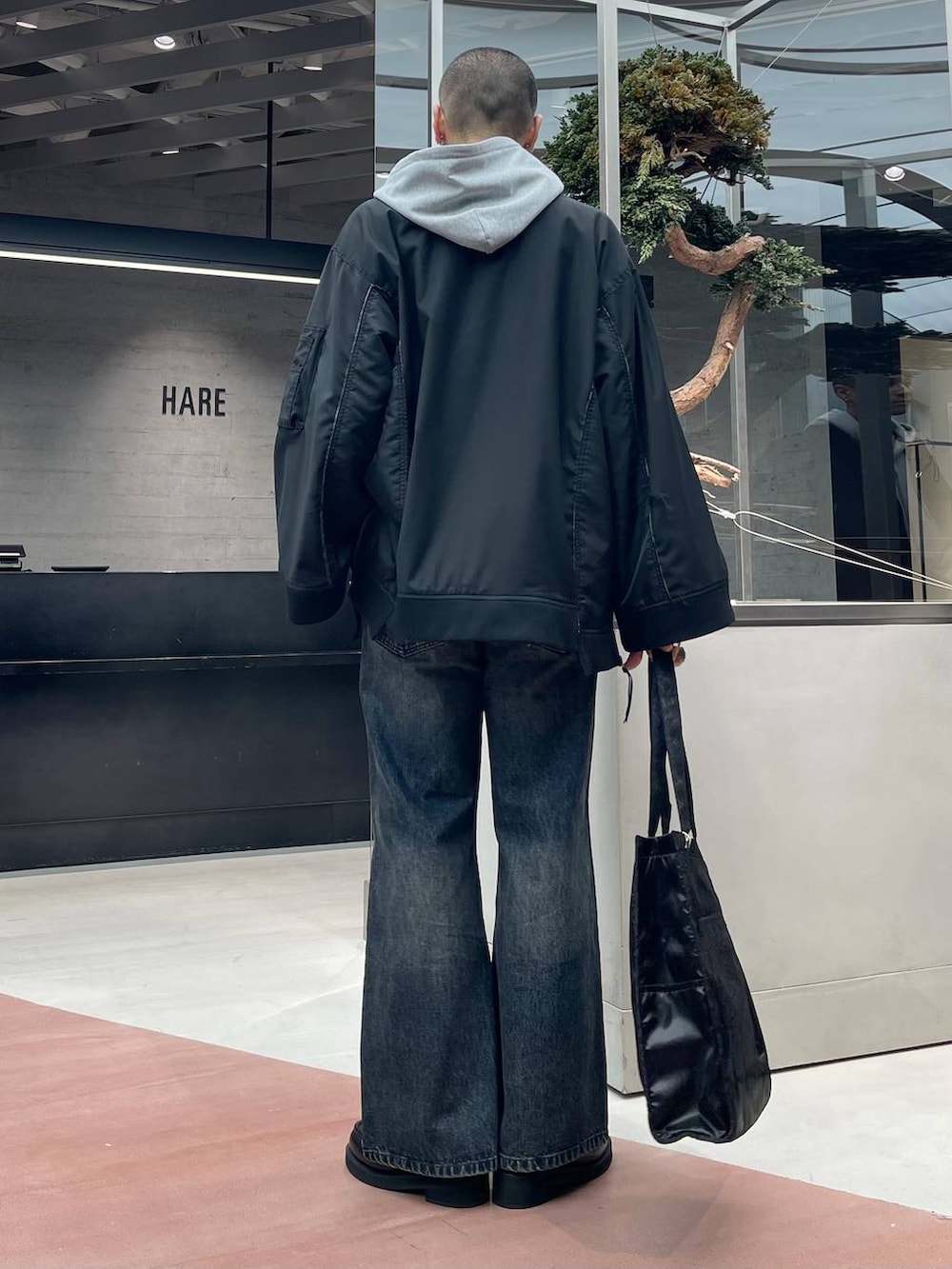 グレー系のパーカー、ブラック系のトートバッグ、ブラック系のローファーを着用したメンズの秋コーディネートの4枚目の写真