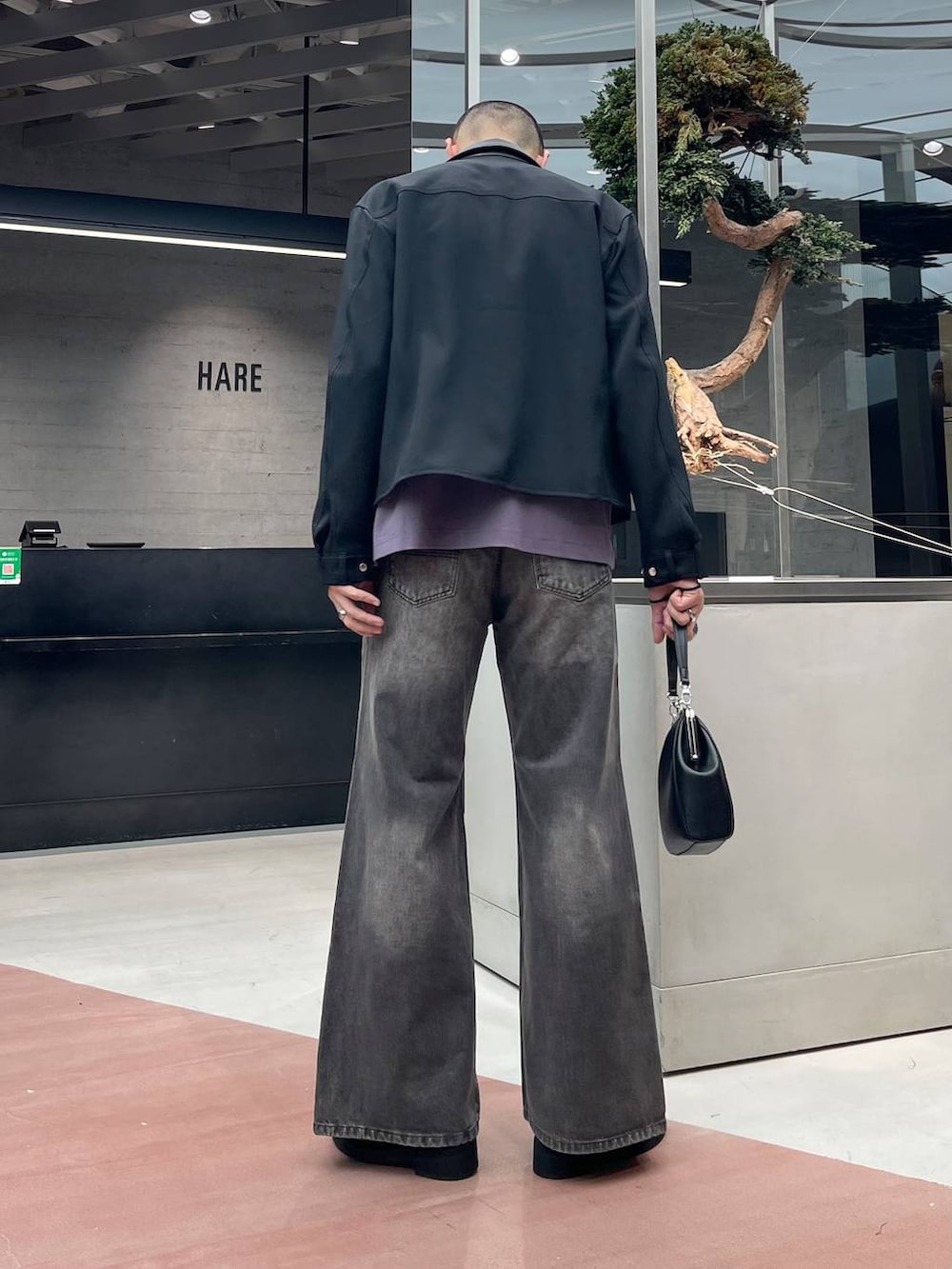 ブラック系のローファー、ブラウン系のデニムパンツ、ブラック系のショルダーバッグを着用したメンズの秋コーディネートの3枚目の写真