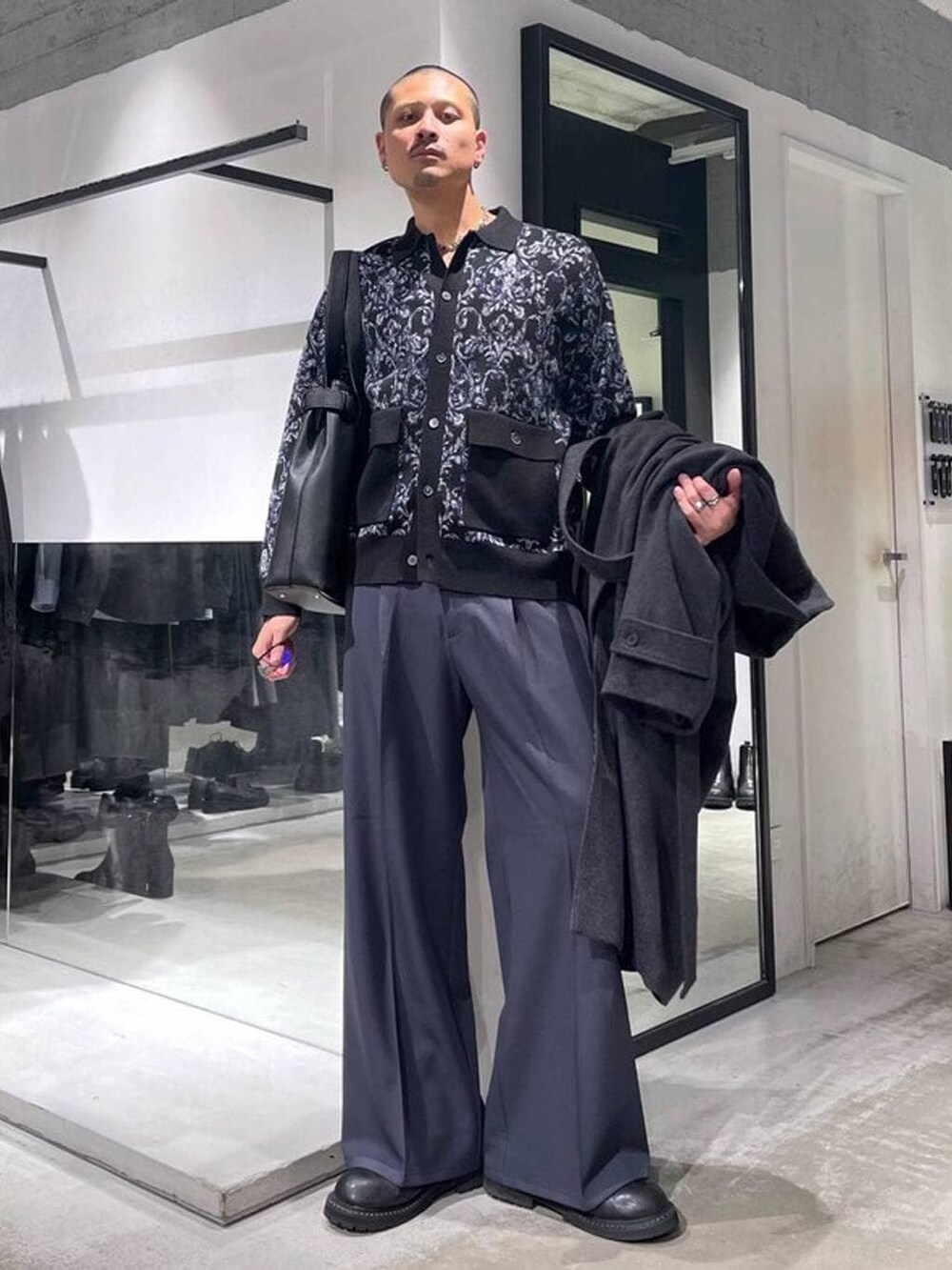 グレー系のチェスターコート、ブラック系のトートバッグ、ブラック系のブーツを着用したメンズの冬コーディネートの5枚目の写真