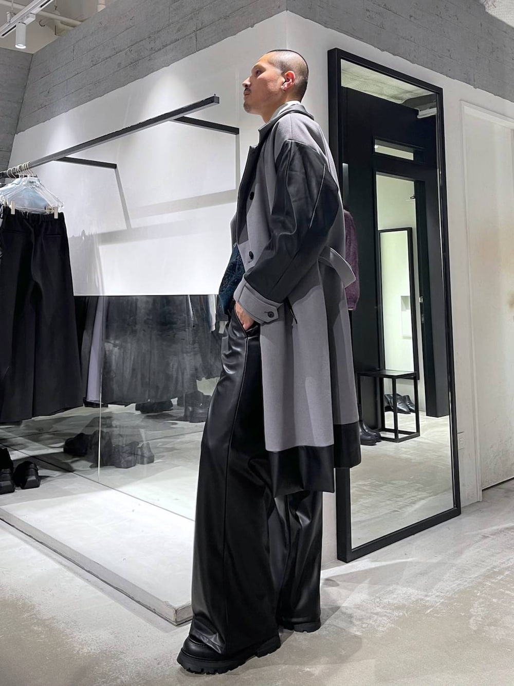 グレー系のトレンチコート、グリーン系のカーディガン/ボレロ、ブラック系のスラックスを着用したメンズの冬コーディネートの2枚目の写真