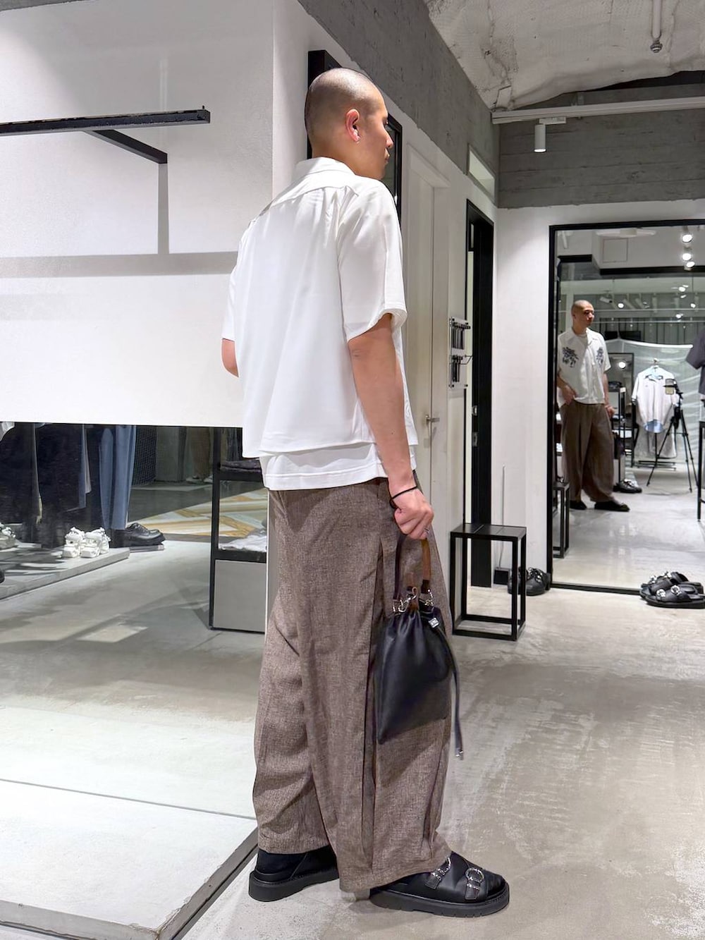 ホワイト系のTシャツ/カットソー、ブラック系のサンダル、ブラック系のショルダーバッグを着用したメンズの夏コーディネートの4枚目の写真