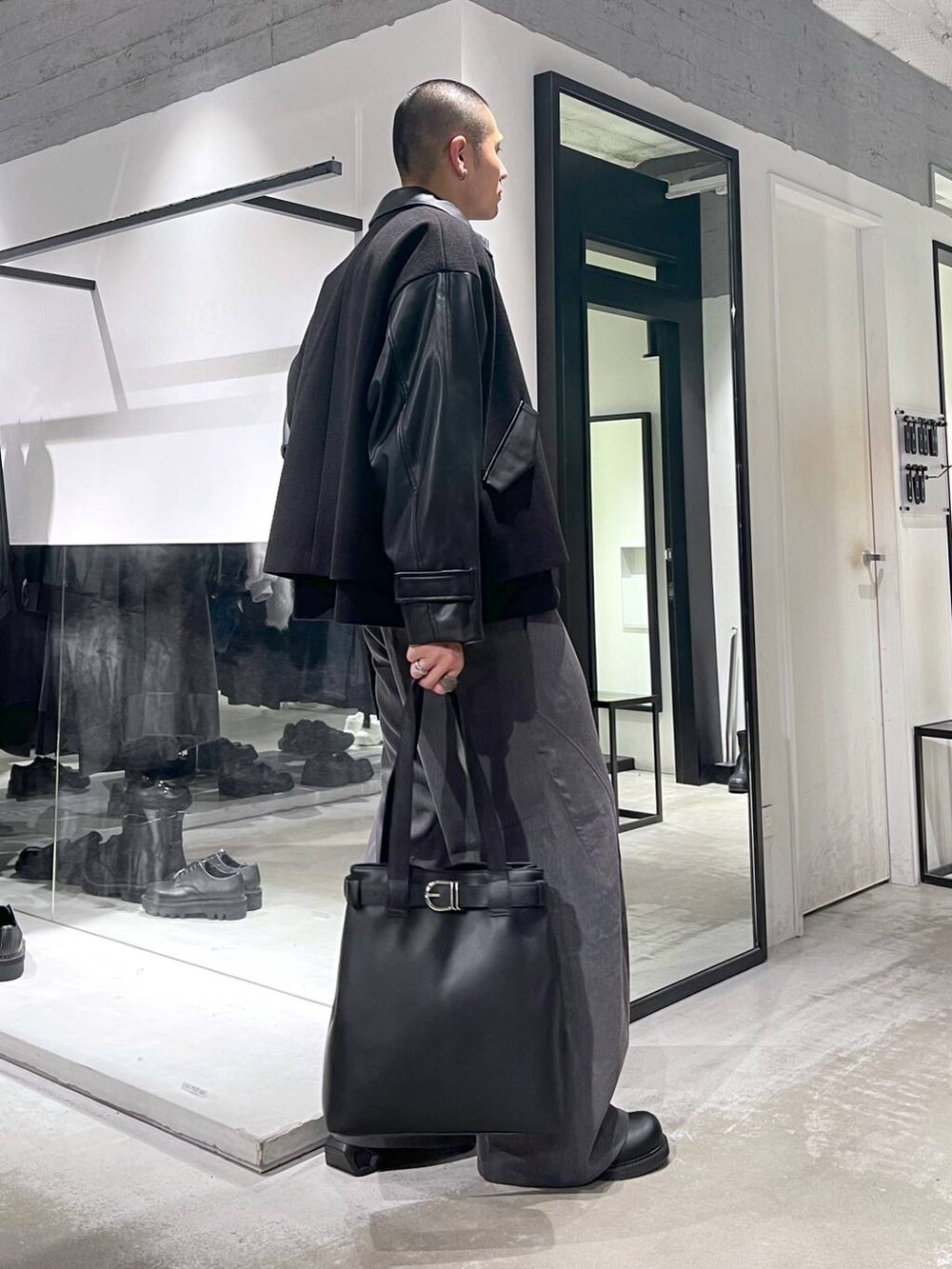 ブラック系のブルゾン、ブラック系のトートバッグ、グレー系のスラックスを着用したメンズの秋コーディネートの4枚目の写真