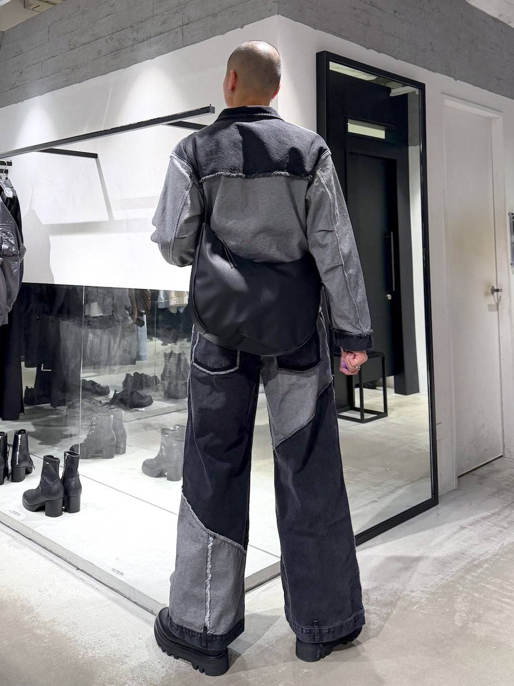 ブラック系のデニムパンツ、ブラック系のドレスシューズ、ブラック系のショルダーバッグを着用したメンズの冬コーディネートの3枚目の写真