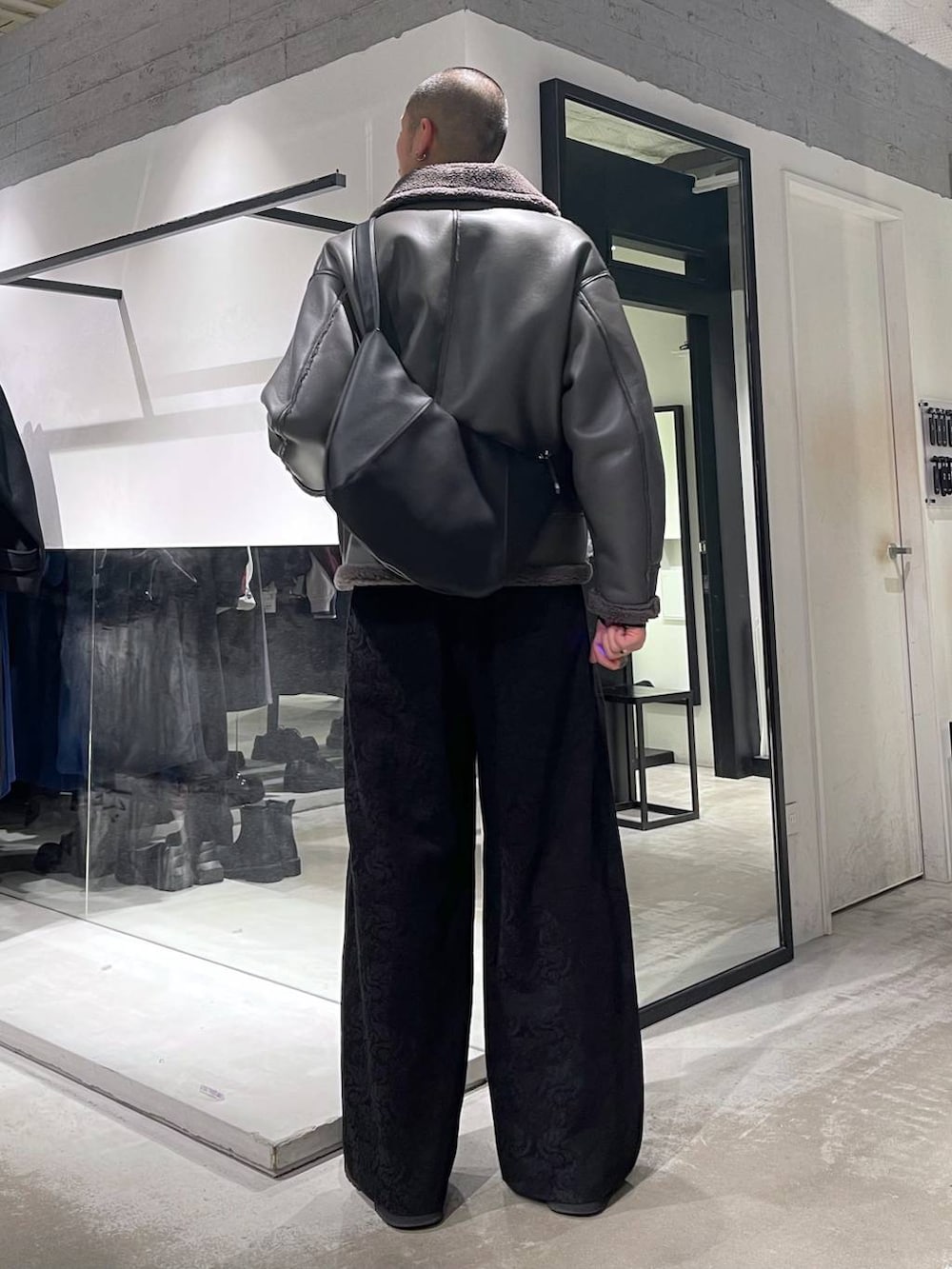 グレー系のブルゾン、ブラック系のブーツ、ブラック系のショルダーバッグを着用したメンズの冬コーディネートの3枚目の写真