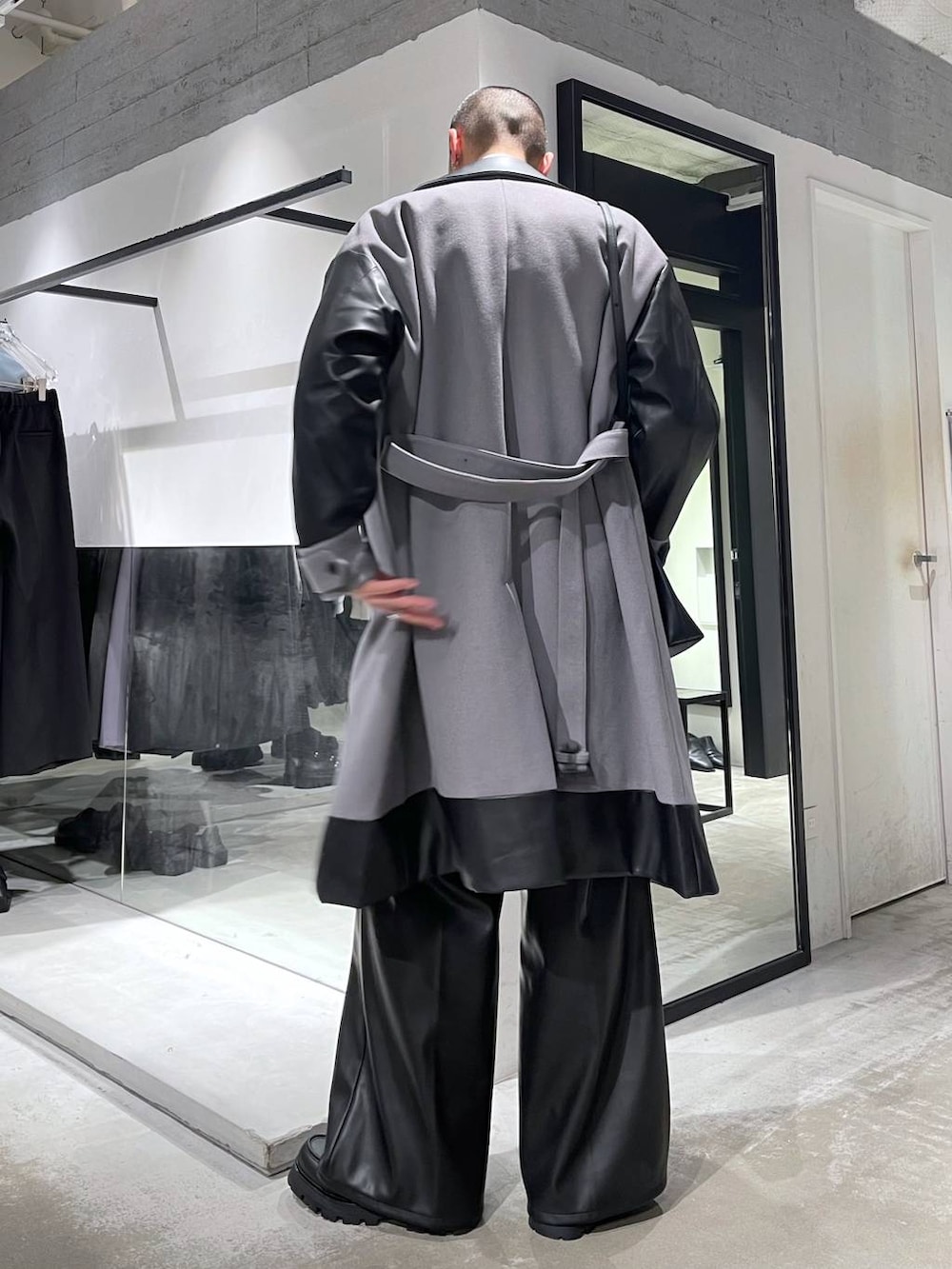 グレー系のトレンチコート、グリーン系のカーディガン/ボレロ、ブラック系のスラックスを着用したメンズの冬コーディネートの3枚目の写真