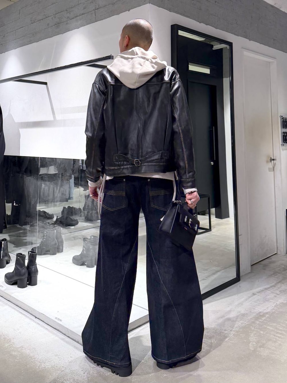 グレー系のパーカー、ブラック系のドレスシューズ、ブラック系のハンドバッグを着用したメンズの冬コーディネートの3枚目の写真