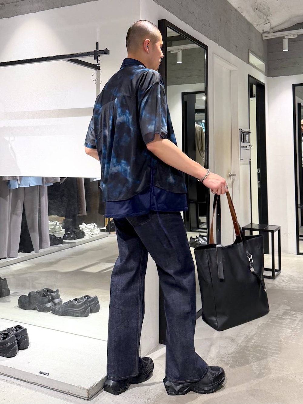ブラック系のスニーカー、ホワイト系のTシャツ/カットソー、ブラック系のトートバッグを着用したメンズの夏コーディネートの4枚目の写真