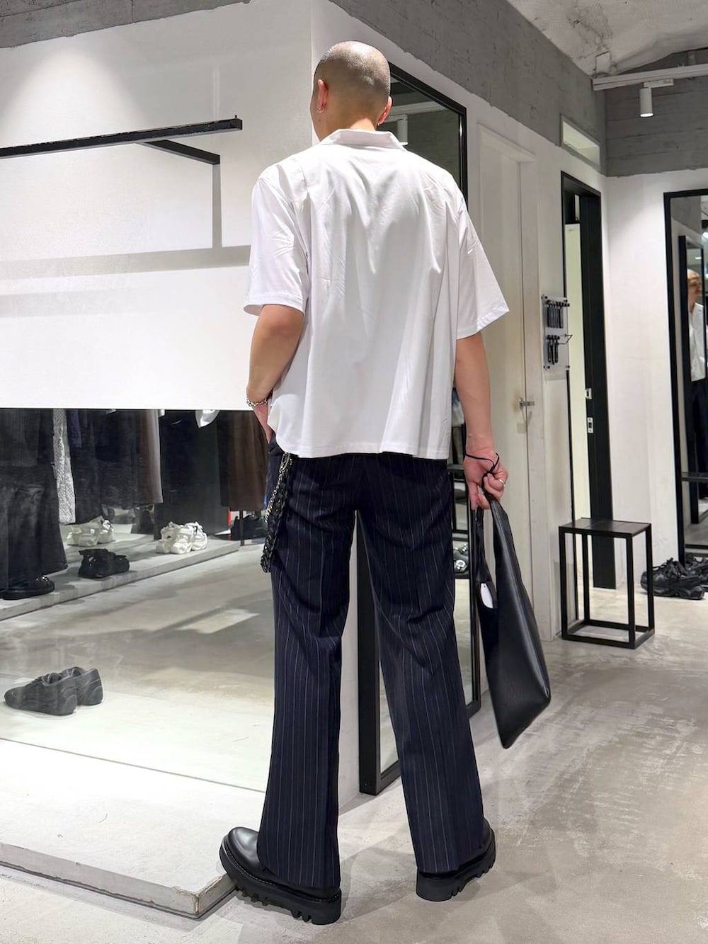ブラック系のトートバッグ、ブルー系のスラックス、ブラック系のドレスシューズを着用したメンズの春コーディネートの3枚目の写真