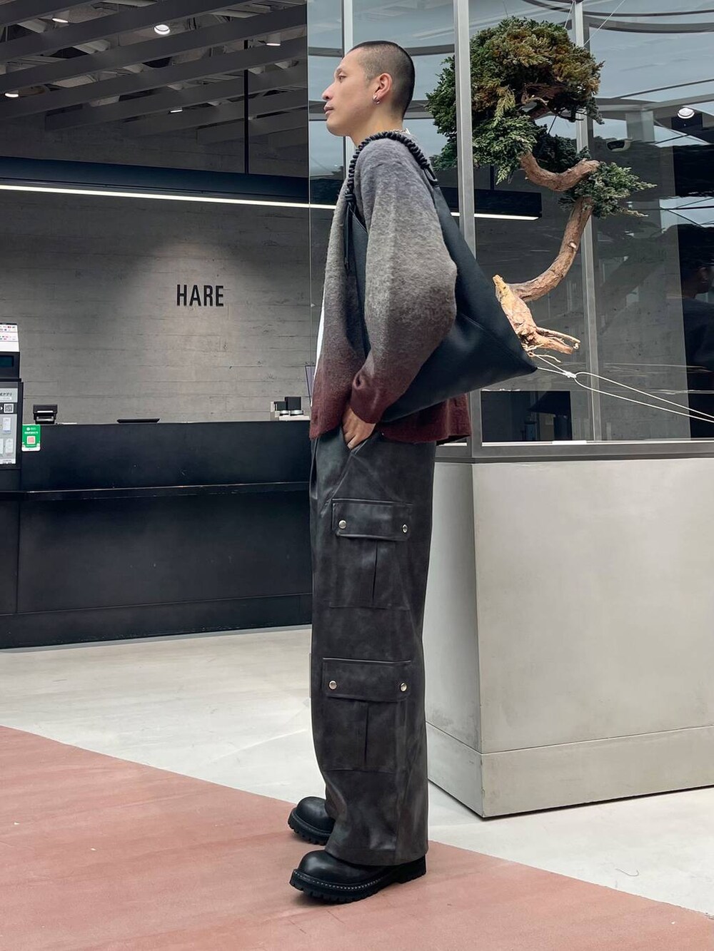 レッド系のカーディガン/ボレロ、グレー系のカーゴパンツ、ブラック系のブーツを着用したメンズの秋コーディネートの2枚目の写真